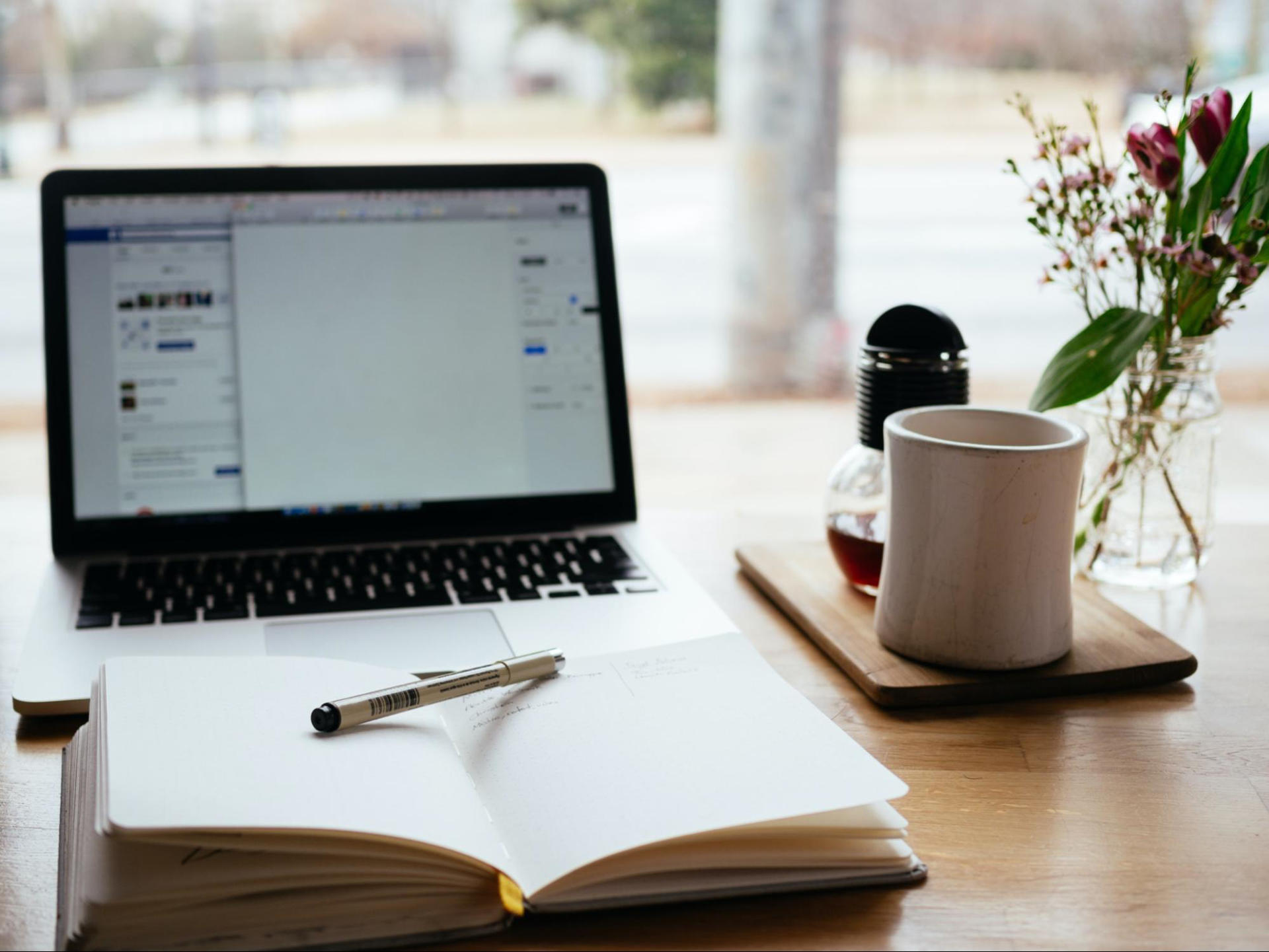 MacBook Pro and a notebook for writing on a desk